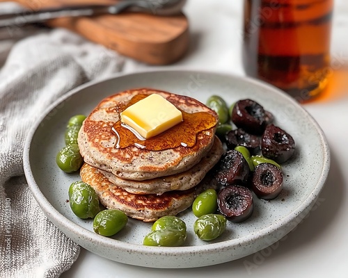 Stacked pancakes with butter, syrup, and olives photo