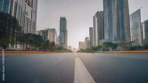 Empty asphalt road in modern city downtown with towering skyscrapers under clear blue sky, urban landscape with no traffic