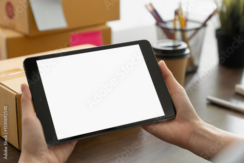 Hand holding digital tablet with a blank screen on table, for putting advertising to promote.