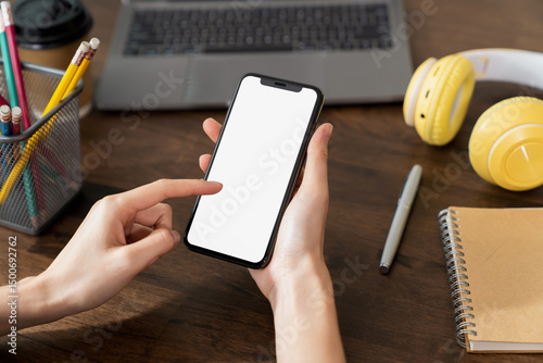 Hand holding smartphone with a blank screen on table, for putting advertising to promote.