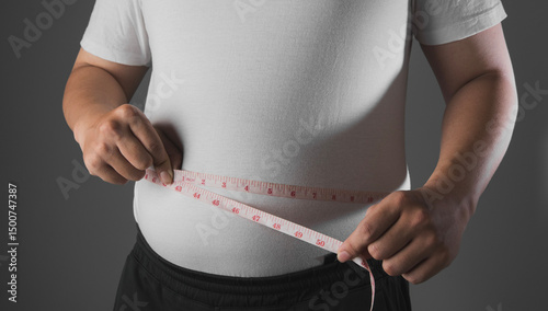 Foto Overweight or obese man with abdominal fat using a tape measure to check his wai