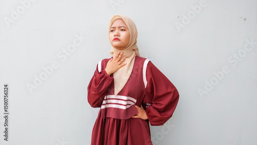 Young Muslim Woman Wearing Hijab Holding Her Sore Throat in Pain, Feeling Unwell Due to Illness or Cold Symptoms, Health Concept on White Background