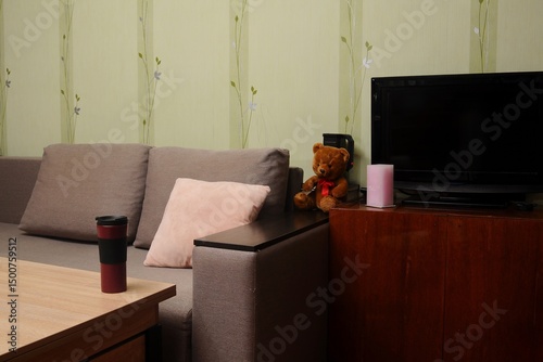 A comfortable living room setting with a teddy bear, sofa, television, and cozy ambiance.