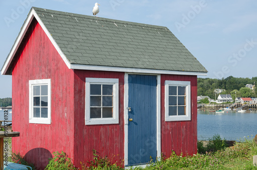 Red wooden fishing shack with a blue door against the clear blue sky on Bailey Island, Harpswell, Maine, New England, USA photo