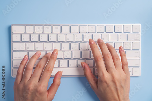 Close up of woman hands typing on computer keyboard on blue background.