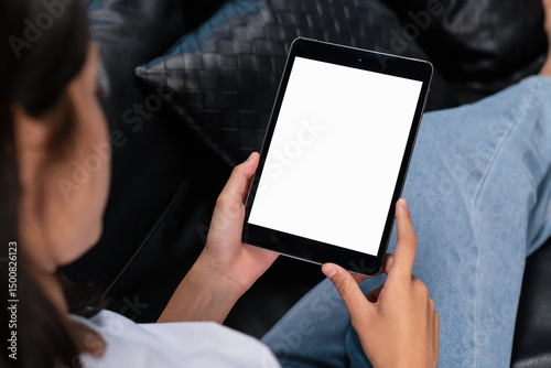 Hand holding digital tablet with blank screen for graphic display montage on the sofa in the living room, mockup display for lifestyle and wireless technology.