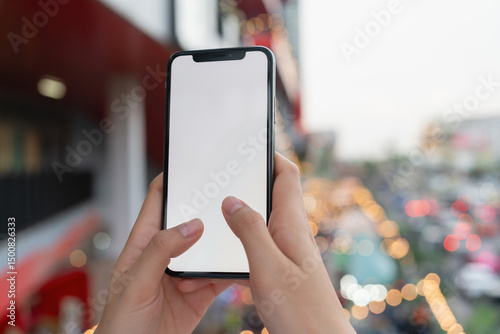 Hand holding smartphone with blank screen for graphic display montage on outdoors background, mockup display for lifestyle and wireless technology.