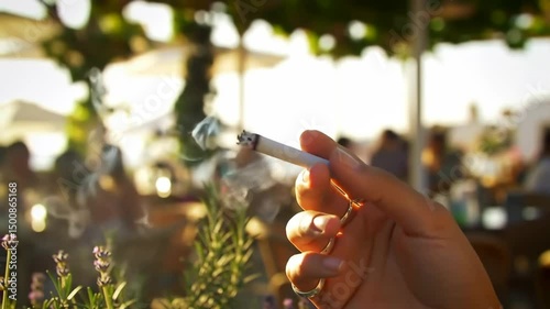 video closeup person hand is holding a lit cigarette in his hand enjoying the atmosphere