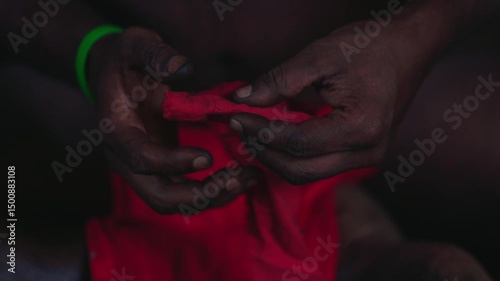 An aborigine in a loincloth makes fire in the traditional way, striking sparks on tinder, lighting a hearth in a hut. An ancient way of making fire in slow motion