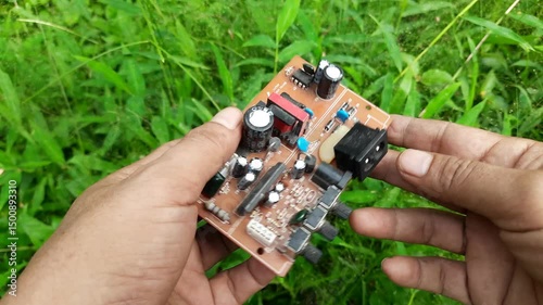 Hands Holding Mini Audio Amplifier PCB with Capacitors and Resistors