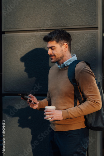 Wallpaper Mural Businessman using smartphone and holding coffee outside office building Torontodigital.ca