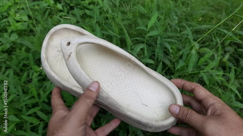 Hands Holding Dirty White Rubber Slippers