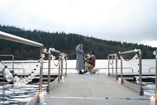 Man proposing marriage to woman on decorated pier photo