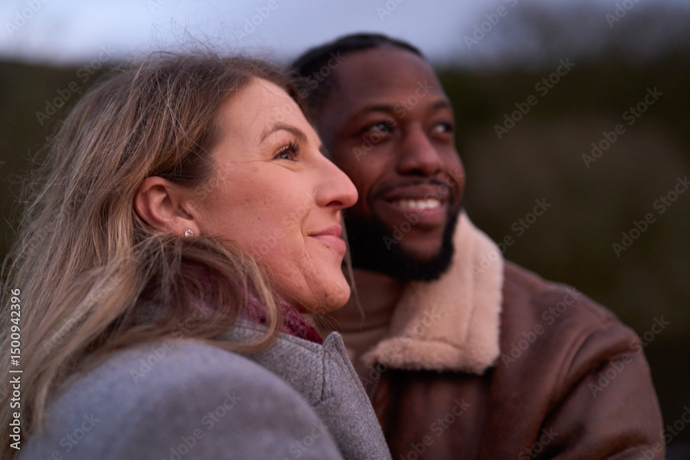 Smiling couple in warm clothing outdoors at dusk Smiling couple in warm clothing outdoors at dusk