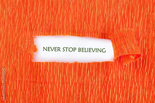 NEVER STOP BELIEVING motivational phrase under the orange paper on a white background