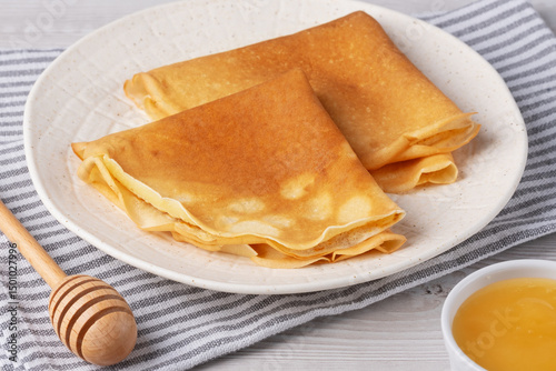 Traditional Russian pancakes with honey on a white wooden table