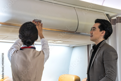 Female flight attendant closing overhead compartment on board