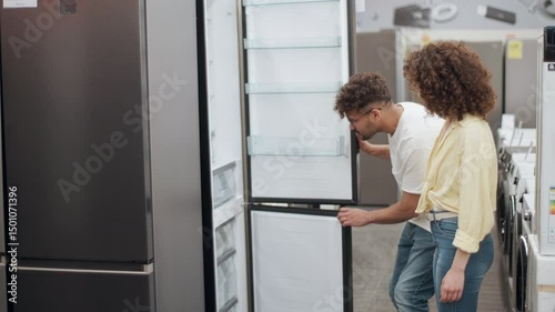 Young couple choosing refrigerator in electronics store in slow motion