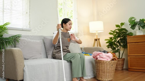 Young housewife feeling tired after doing housework She was sitting on the sofa in the living room with house cleaning supplies.