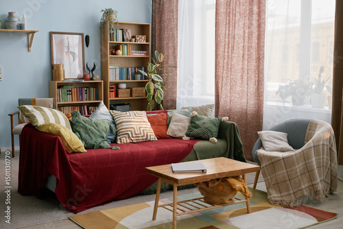Interior of bright and inviting living room with comfortable couch adorned with colorful throw pillows, surrounded by houseplants, bookshelves, and soft lighting