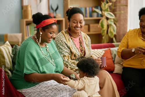 Foto Young Black mother holding hands of little daughter supporting girl while baby l
