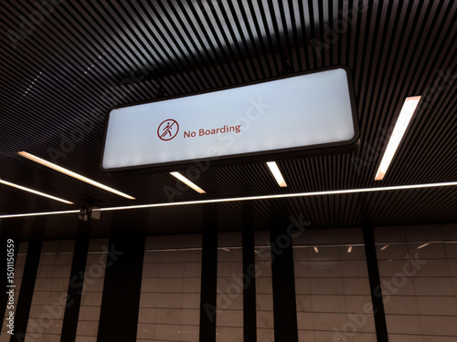 Fototapeta Naklejka Na Ścianę i Meble -  Well lit modern metro station interior with large illuminated No Boarding sign hanging from the ceiling, emphasizing rules and structure in urban public transportation spaces