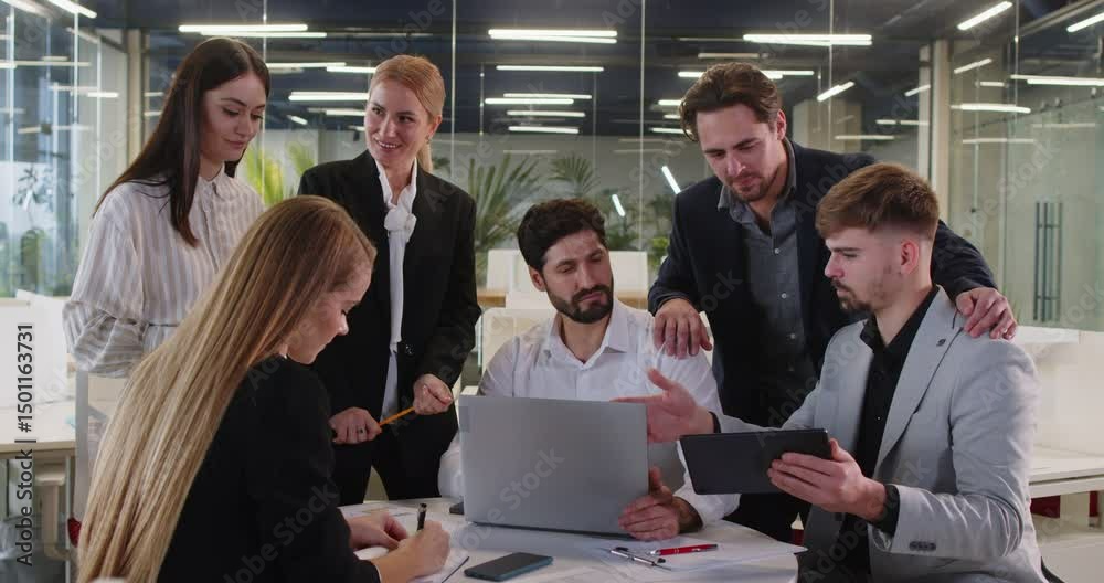 Team of business people or colleagues collaborating during a meeting in the office. Working together using a laptop, highlighting teamwork, productivity, and a professional business atmosphere.