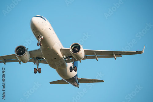 Close-up of a passenger airplane approaching the airport, preparing to land. Blue background. Clear sky.