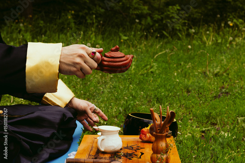 Photography Teapot in hands of a man wearing kimono outdoors