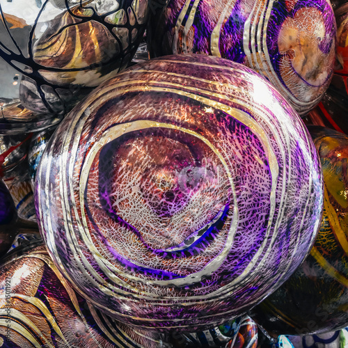 Artistic Sphere: Close-up shot of many spherical artistic glasswork exhibits a mesmerizing dance of purple, silver, and gold swirls, captured in stunning detail photo