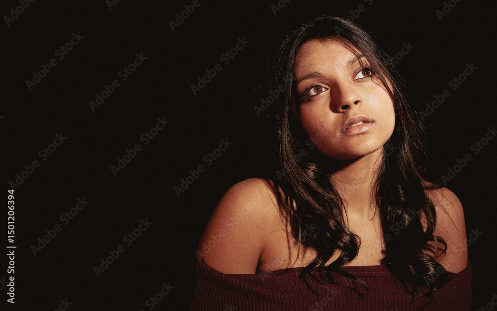 Fototapeta premium Brown Eyed Contemplation. A candid and thoughtful moment from a beautiful young mixed race Anglo-Indian female model. From a series of images with the same model.
