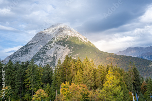 The breathtaking mountain landscape showcases vibrant trees and features dramatic skies that captivate the senses