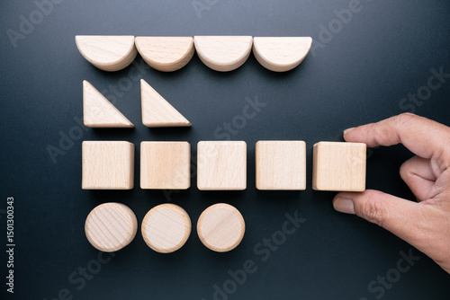 Hand arranging geometric wooden toys so that each shape is in a row, category concept