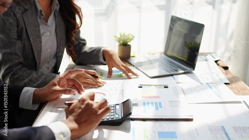 Young colleagues discuss business and analytical price charts using calculators and laptops to calculate financial, tax, accounting, statistics and analytical research ideas.