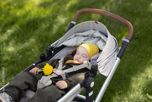 Little girl sleeping in stroller in the park. Portrait of a child sleeping calmly in push chair outdoor. Children day sleep
