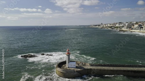 Drone flies backwards and lowers next to Farolim de Felgueiras lighthouse on the Atlantic coast in Porto, Portugal