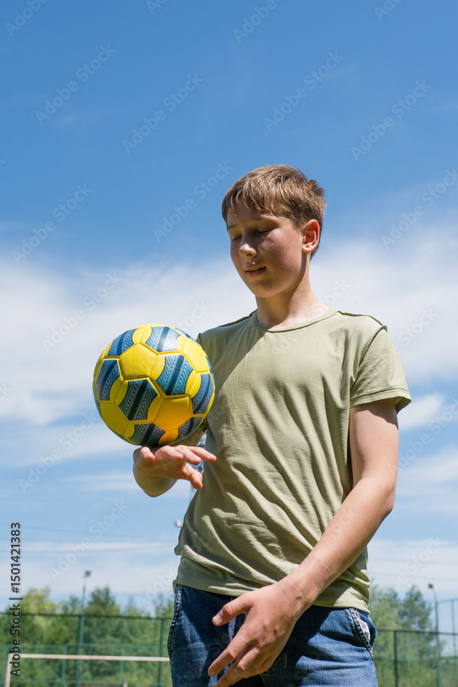 Naklejka premium Teenager skillfully juggling a soccer ball outdoors on a sunny day. A summer sports activity.