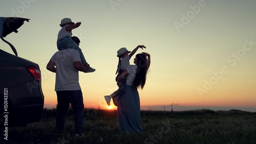 Dad with child, daughter on his shoulders, mom, children dance and admire beautiful sunset. Parents and children stopped at campsite by car. Happy family travels by car. Big family, Travel by car. Kid