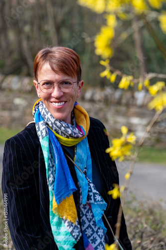 A smiling middle-aged woman in a business look with a colourful scarf in spring.