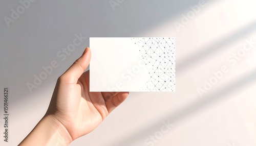 Elegant Hand Holding Blank Card with Geometric Pattern and Soft Light in Minimalistic Setting