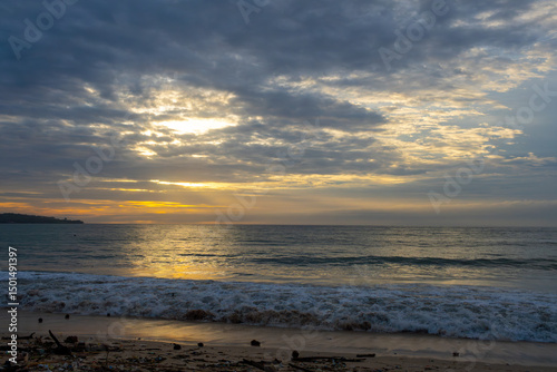 The sky is cloudy and the sun is setting over the ocean