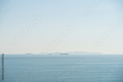 Foggy Light Blue Sea with Small Islands Near Horizon