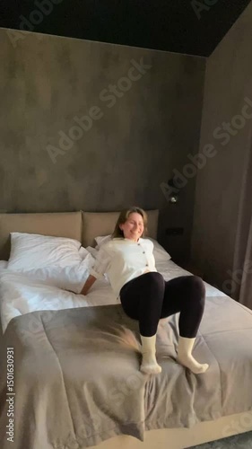 a young woman jumps on the bed in a hotel room