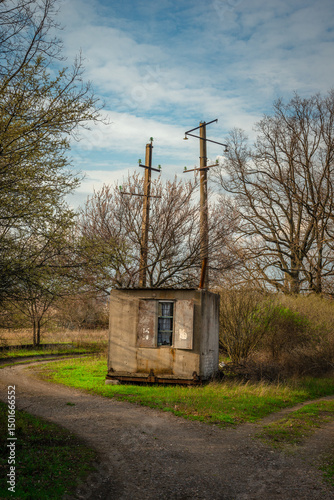 Fork in a Rural Dirt Road with a Small Utility Building and Bare Trees Under a Wide Sky