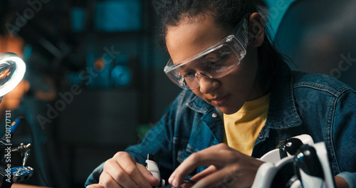 A cheerful teenager works in her room under soft evening light, connecting circuits and building her own robot, showing a strong interest in electronics, robotics, and scientific fields.