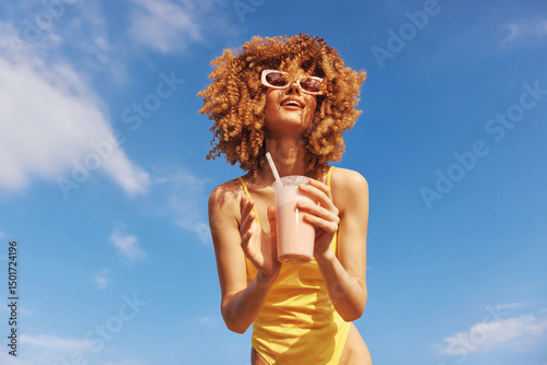 Photography Young woman enjoying a refreshing drink in a vibrant summer outfit against a cle