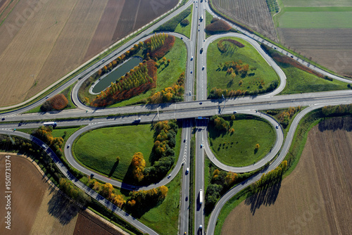 Aerial view of a beautiful roundabout and winding highway surrounded by greenery and fields, France.