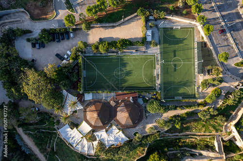 Aerial view of a beautiful urban landscape featuring a soccer field, recreational area, and surrounding buildings with trees, Polignano a Mare, Bari, Italy.