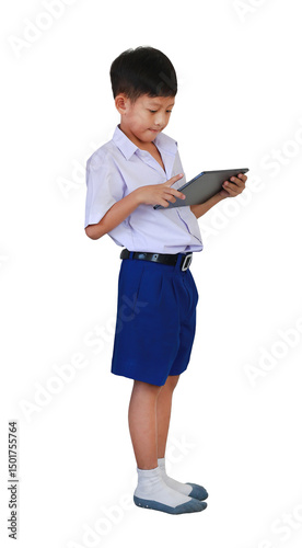 Portrait of Asian boy in primary or elementary school uniform using tablet computer while standing isolated on white background. Image side view and full length.