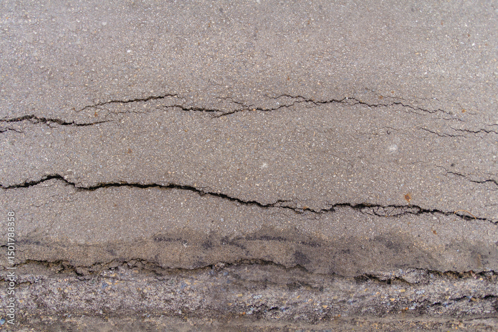 Fototapeta premium Cracks in the asphalt road surface are caused by poor road construction and failure to compact the road surface before laying the asphalt. The background of the asphalt on the road surface has cracks.